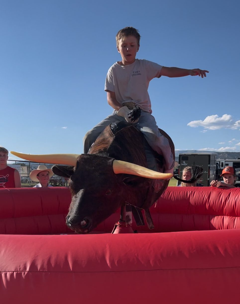 A young rider on the mechanical bull outdoors at an event