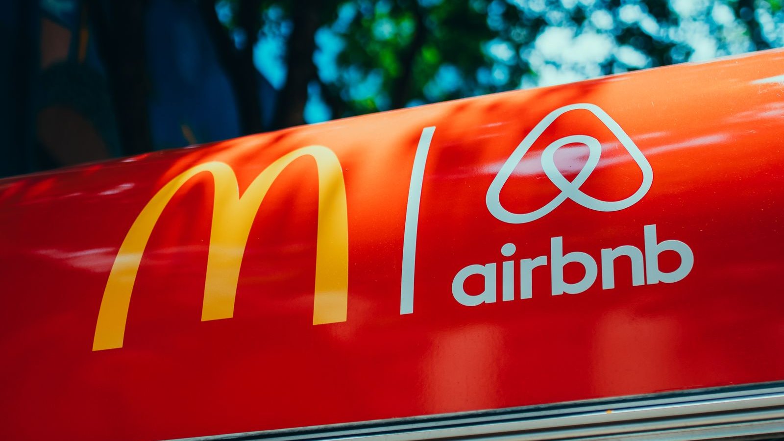 Recognizable brand logos displayed on a red surface with a tree in the background