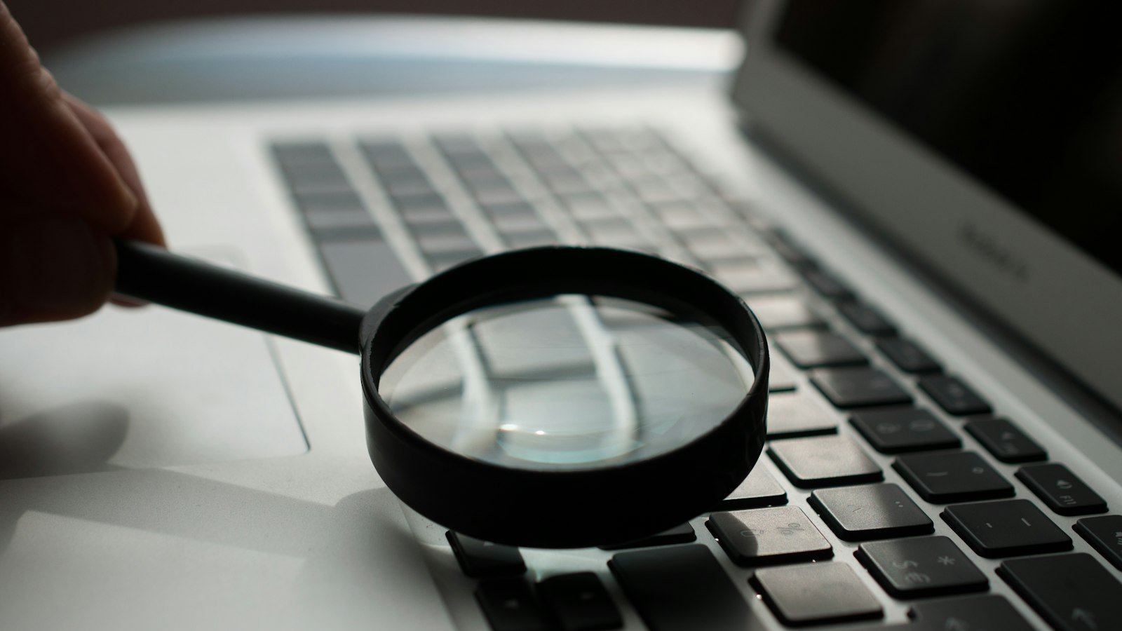 Magnifying glass next to a laptop, representing an SEO search